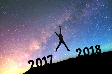 Naklejka premium Silhouette young man Happy for 2017 new year background on the Milky Way galaxy pointing on a bright star. dark sky tone . Vintage grain tone.