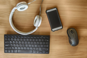 Computer workplace, top view: keyboard, mouse, smartphone, headphones (earphones) on a wooden...