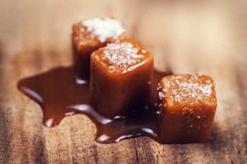 Salted  caramel candies and caramel sauce on wooden background, Golden Butterscotch toffee caramels.