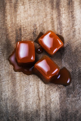 Organic caramel candies and caramel sauce on wooden background, Golden Butterscotch toffee caramels.