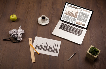 Business laptop with stock market report on wooden desk