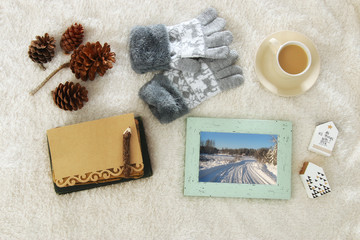 Empty note and cup of cappuccino over cozy and warm fur carpet. Scandinavian style design. Top view.