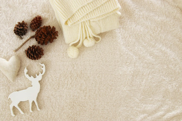 Fototapeta na wymiar Knited sweater, pine cones, golden heart and reindeer over cozy and fur carpet. Top view.