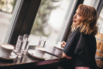 Pretty girl smiling and drinking coffee in  a bar