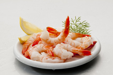 Steamed Jumbo headless shrimps with deli leaves and Lemon on white plate on white background 