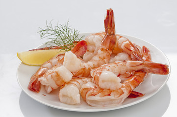 Steamed Jumbo headless shrimps with deli leaves and Lemon on white plate on white background 