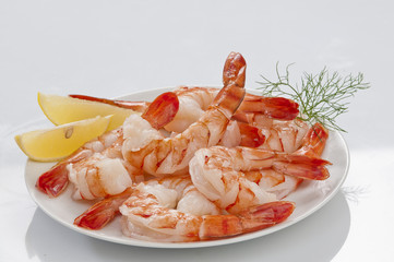 Steamed Jumbo headless shrimps with deli leaves and Lemon on white plate on white background 