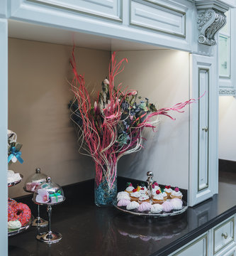 Luxurious kitchen in classic style. Vase with flowers and the dessert dishes are set on a black marble countertop