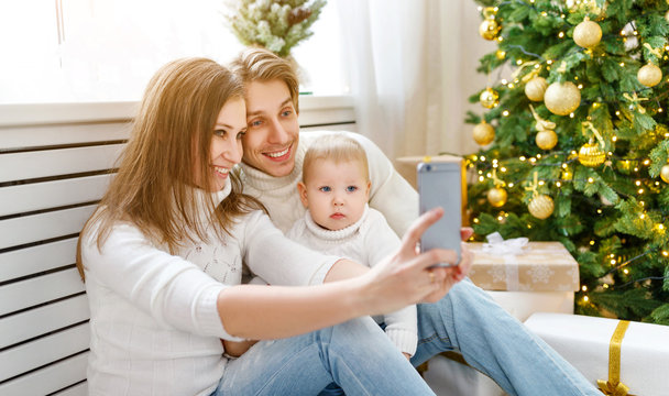 happy family photographed on phone, makes selfies in Christmas morning
