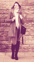 Fototapeta na wymiar girl in hood standing near stone wall