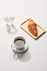 Breakfast with croissant and black coffee composition.