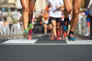 Marathon running in the light of evening,runners running on city road,detail on legs - obrazy, fototapety, plakaty