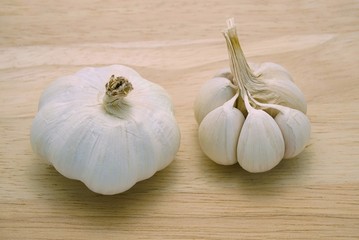 Whole garlic bulbs with and without outer shell on wooden table background. A type of cooking ingredient. Herbal plants and healthy food related to blood pressure, antibiotics, etc.