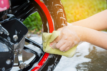 motorcycle clean,female hand with yellow foam sponge washing a motorcycle.