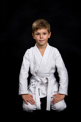 Smiling sitting karate fighter in a brand new kimono ready for training