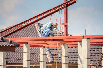 Naklejka premium welder workers installing steel frame structure of the house roof at building construction site