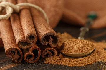 Cinnamon sticks and powder on rustic wooden Board closeup. Spices. Seasonings. Selective focus