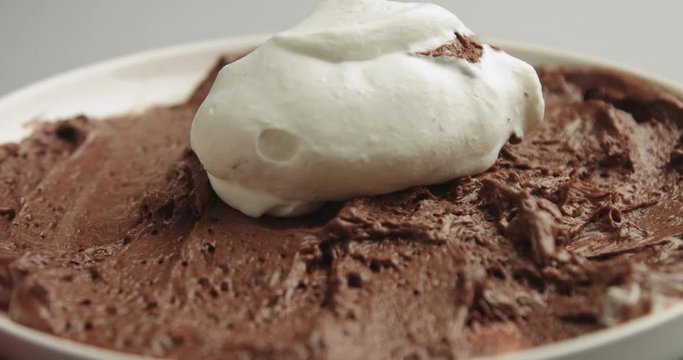 Arranging whipped cream on top of a plate of artisanal fresh chocolate mousse