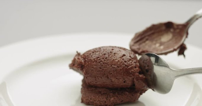 Serving soft chocolate mousse with whipped cream and cocoa powder on white plate