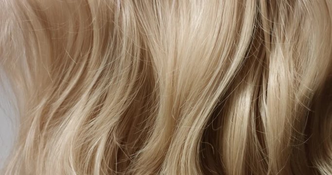 Pan video of woman's long wavy blond hair on white background