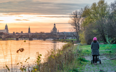 Fototapeta na wymiar Spaziergang mit Kinderwagen bei Sonnenuntergang in Dresden