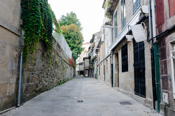 Empty street in town's historic quarter Pontevedra (Spain). Masonry walls steel gratings in door and coffee cup symbol in a coffee shop