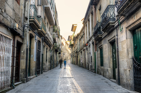 Two people walking in a street in the historical center of Pontevedra early in the morning