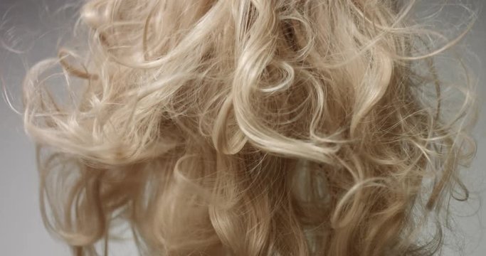 Close up video of blowing out long wavy blond woman's hair on white background