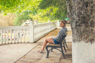 Fototapeta premium Urban woman sitting on a bench of a park and breathing deep fresh air