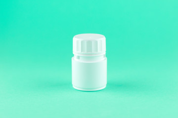 Close up white pill bottle on aquamarine background with copy space. Focus on foreground, soft bokeh. Pharmacy drugstore concept