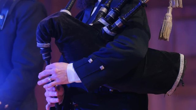Bagpipe player plays musical instrument at the stage