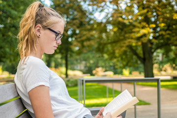 Eine junge Frau auf einer Bank liest ein Buch