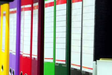 colored binders in a row on shelf, shallow depth of field