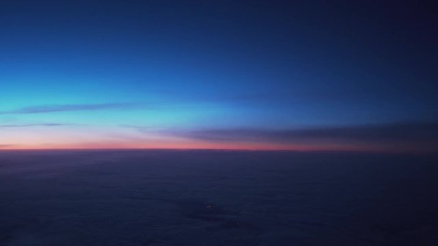 Handheld shot of clouds in early morning during flight on a plane grainy