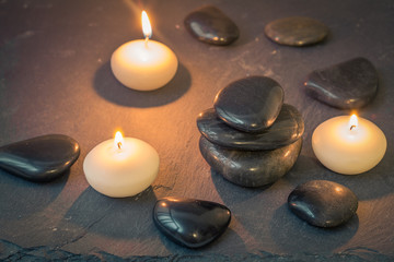 black stones and burning candles on dark background