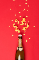 Party attributes fly out from botle of champagne wine on red background