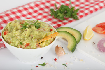 Bowl of guacamole with fresh ingredients on a white table