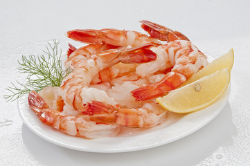 Steamed Jumbo headless shrimps with deli leaves and Lemon on white plate on white background 