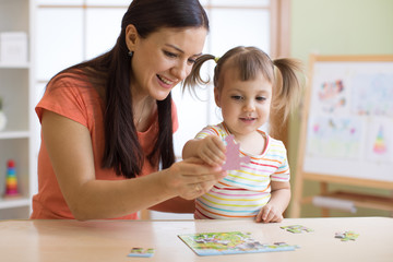 mother and daughter doing playing puzzle toy together on the table in children room