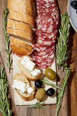 Cheese, vegetables, fruits and spices. Bread, olives and crackers. Mediterranean diet and cuisine. Dark background. Top view.