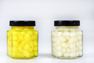 Tasty seasoned vegetables in jars. Kitchen pantry with mortar. White background,