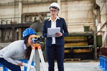 Pensive building surveyor making notes about measurements while working with female engineer...