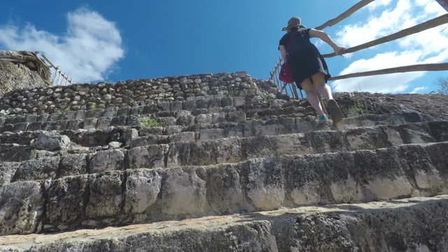 A gimbal shot of woman hiking up mayan ruins at ek balam