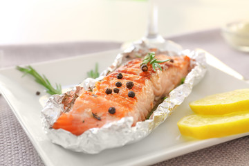 Plate with tasty grilled salmon and lemon slices on table, closeup