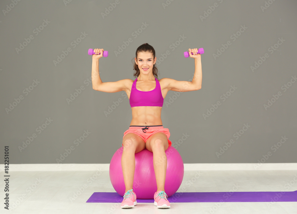 Wall mural Sporty young woman training in gym