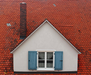 Białe okno z niebieskimi okiennicami na czerwonym dachu z kominem - obrazy, fototapety, plakaty