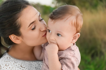 Beautiful young mother holding cute baby boy, outdoors