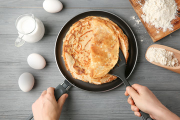 Woman holding pan with delicious thin pancakes on table © Africa Studio