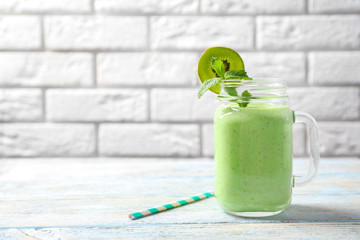 Mason jar with green milkshake on table