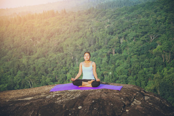 Naklejka na ściany i meble Asian women relax in the holiday. Play if yoga. On the Moutain rock cliff. Nature of mountain forests in Thailand